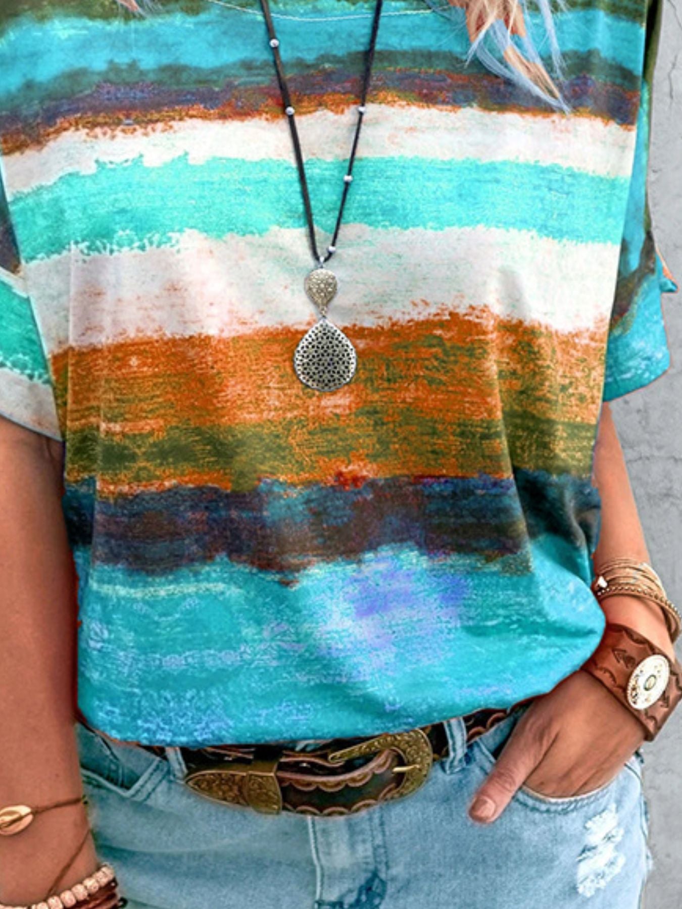 Colorful striped shirt with a necklace and bracelets on a neutral background