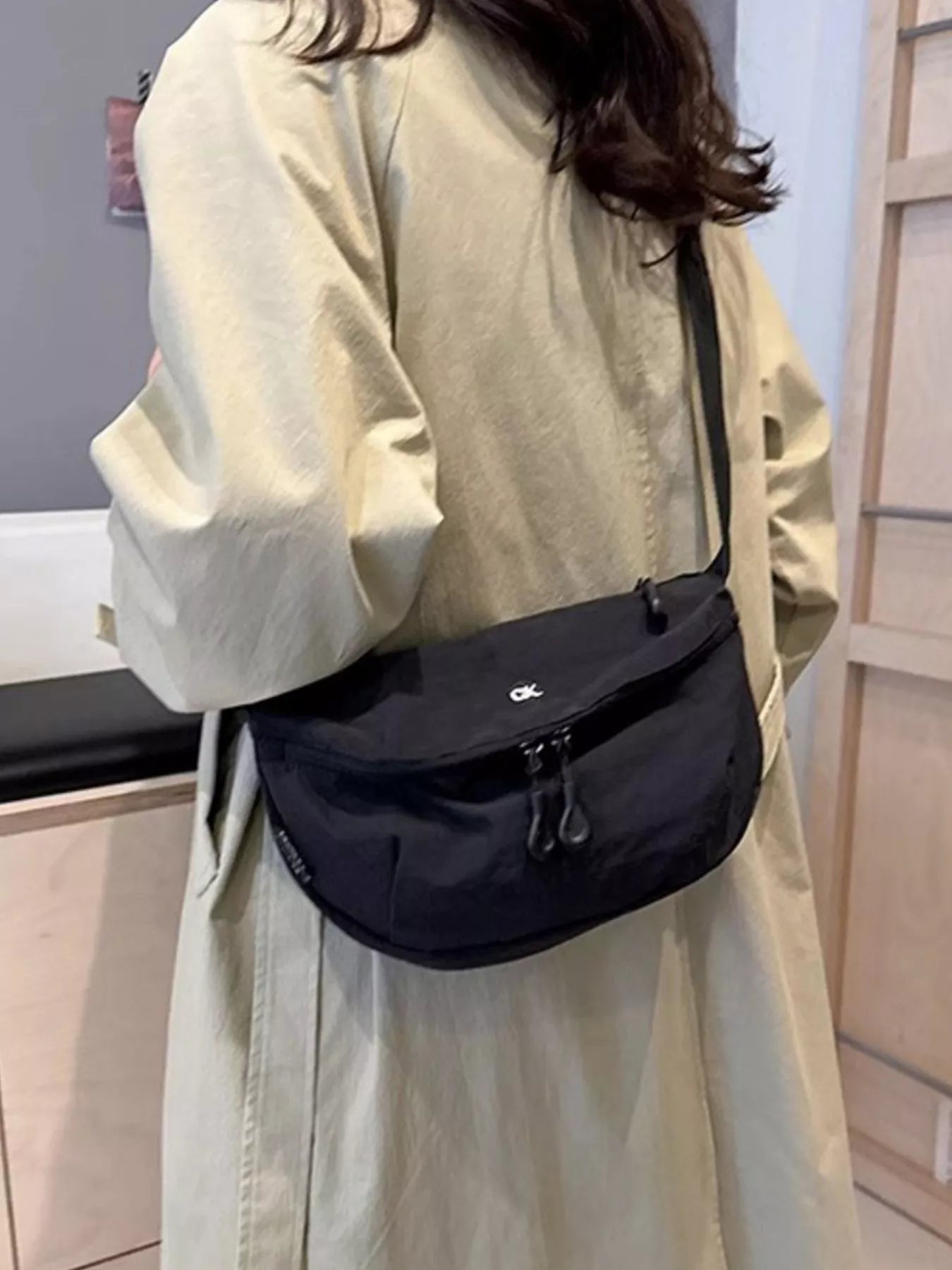 Person wearing a black crossbody bag indoors