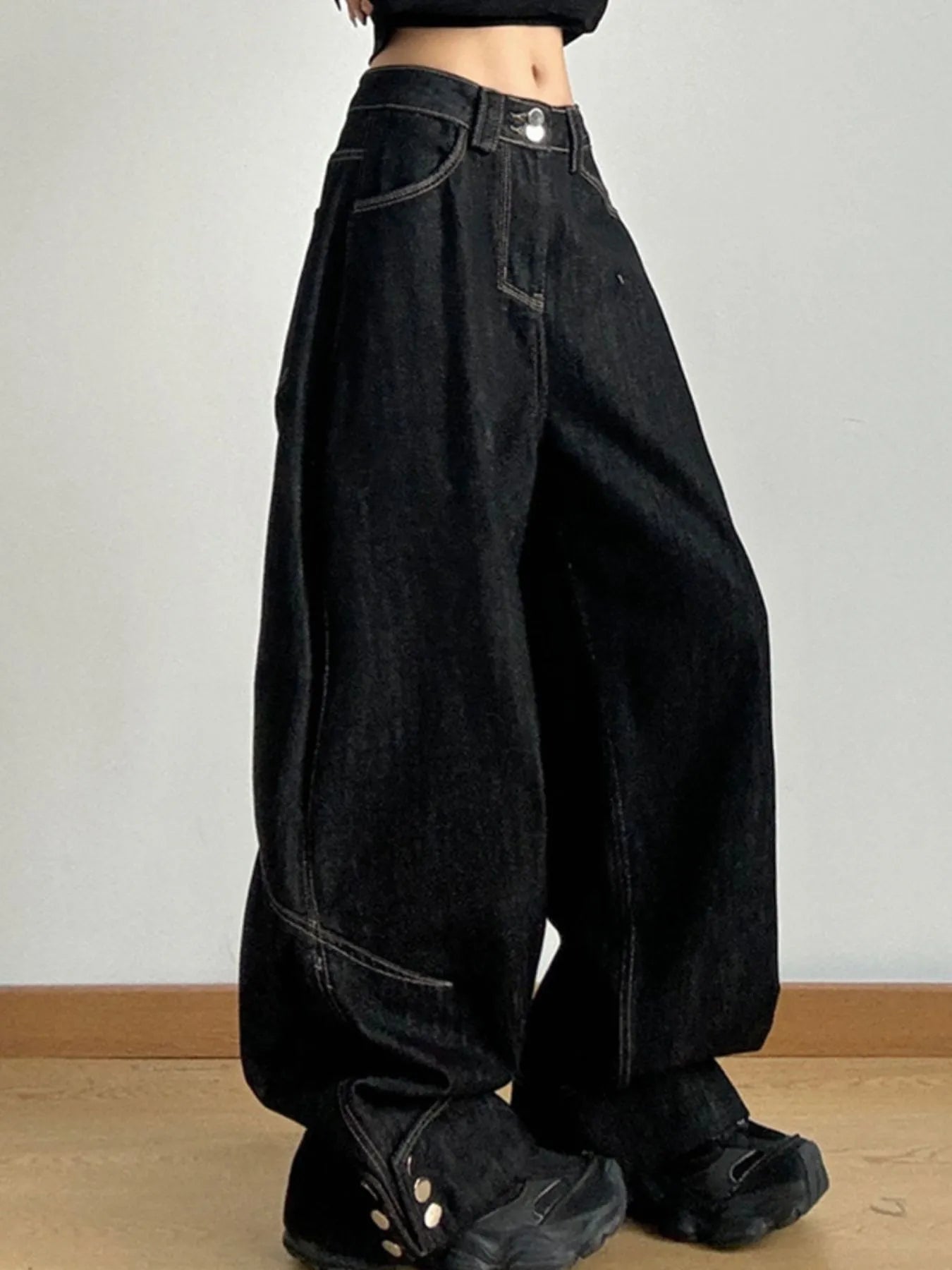 Person wearing black wide-leg jeans on a plain background