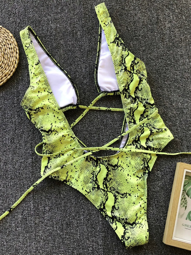 Neon green snake print bikini set on a textured gray surface.