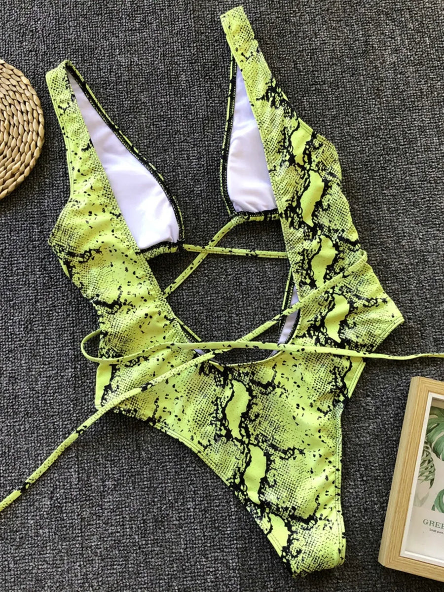 Neon green snake print bikini set on a textured gray surface.