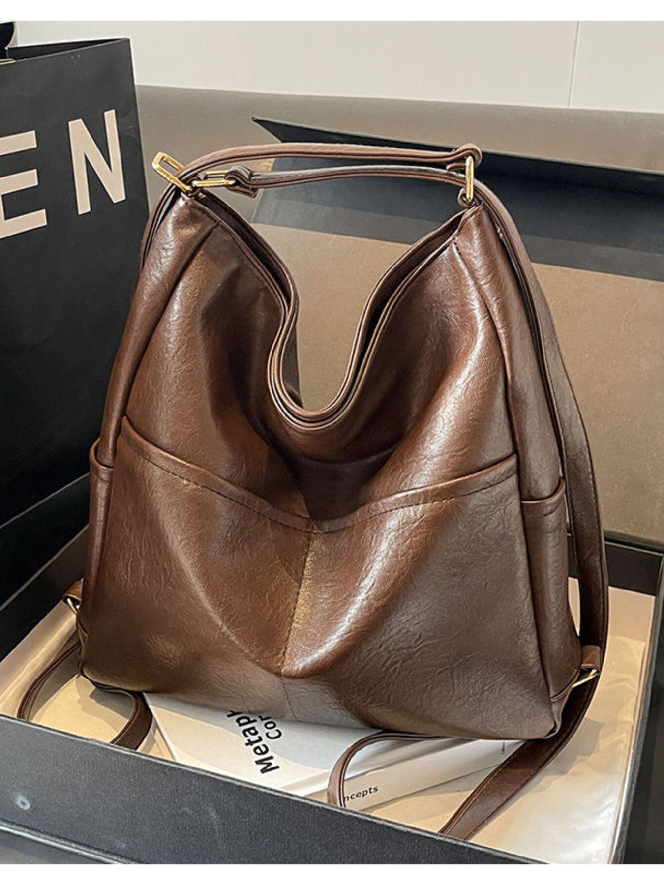 Brown leather handbag on a reflective surface with a blurred background