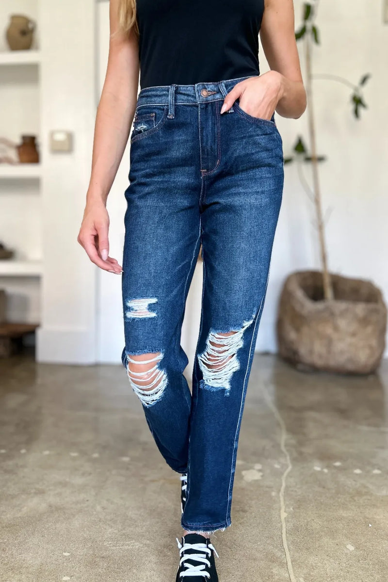 Person wearing blue distressed jeans indoors.