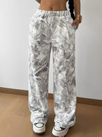Person wearing white floral patterned pants against a plain background