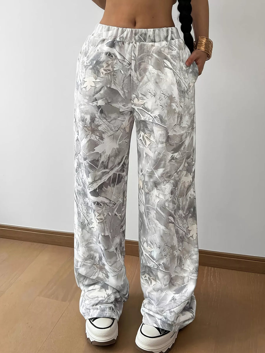 Person wearing white floral patterned pants against a plain background