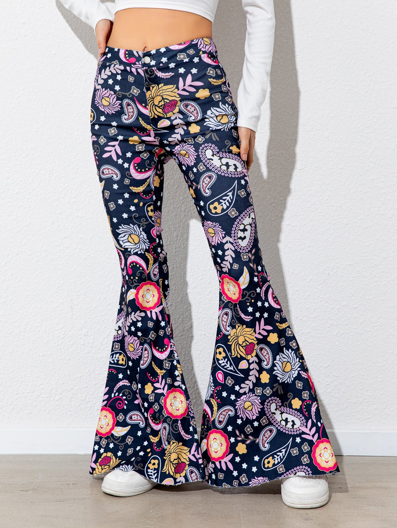 Flared pants with colorful floral pattern worn by a person on a white background