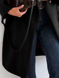 Person holding a black bag with a plain background