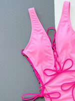 Pink bikini set with lace-up details on a gray background