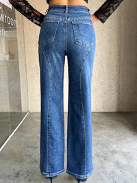 Person wearing blue jeans standing in a room with a neutral background
