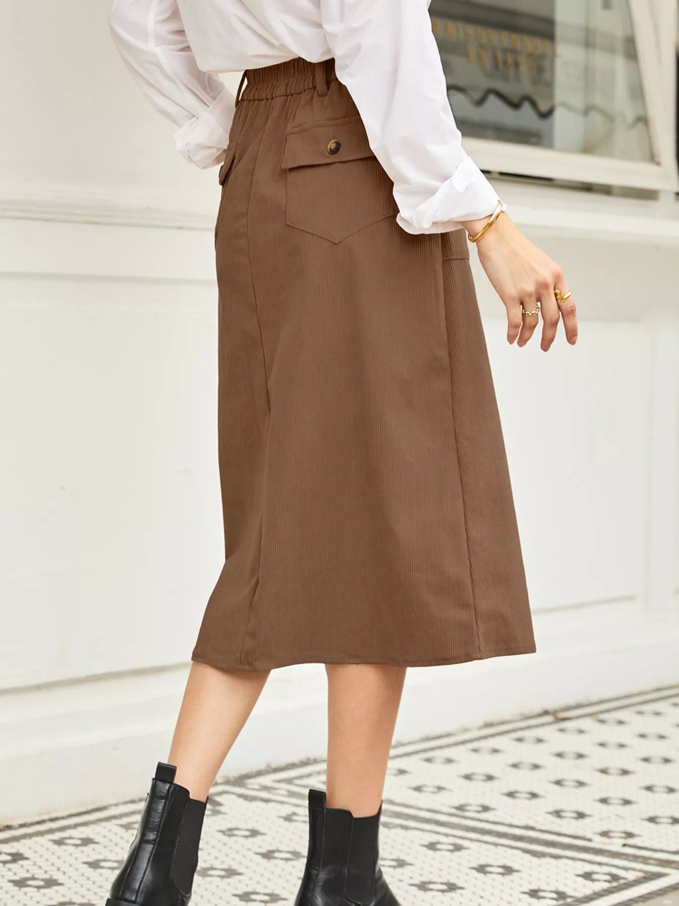 Person wearing a brown skirt and white blouse on a light background