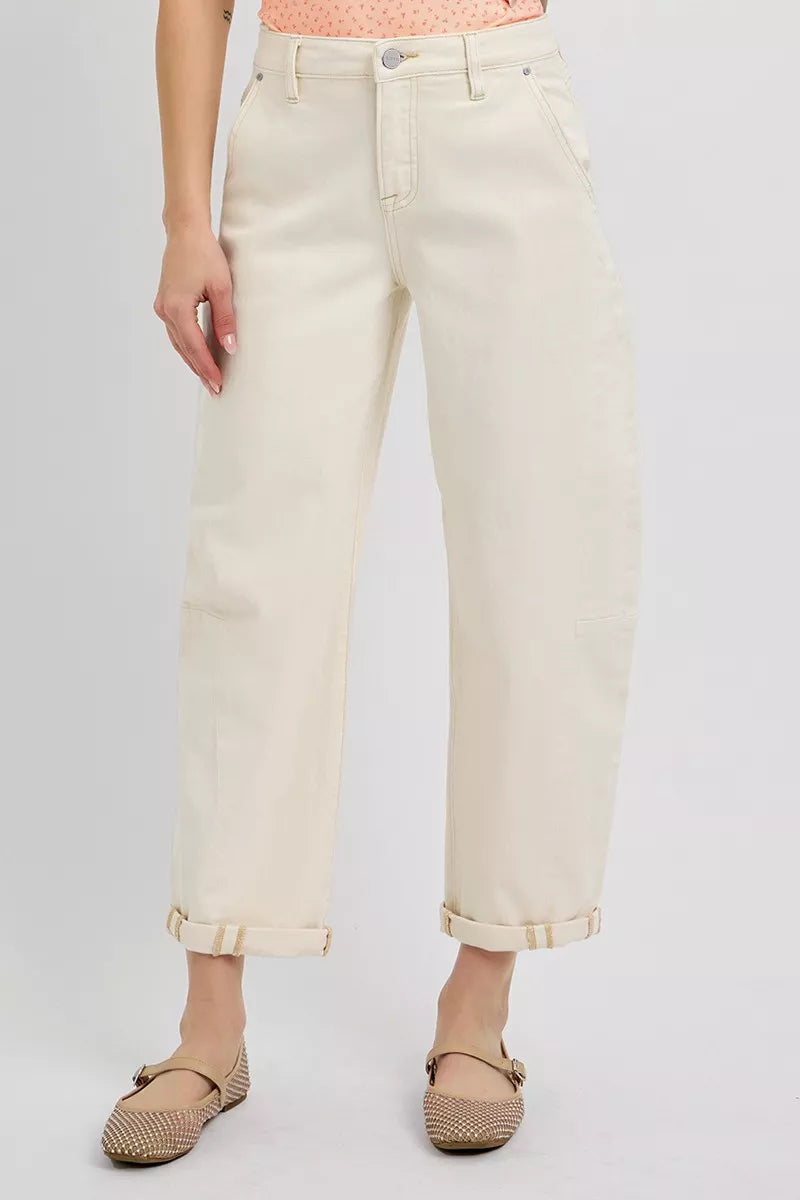 Person wearing light-colored jeans and beige shoes on a plain background