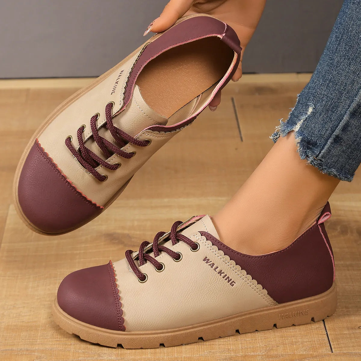 Pair of maroon and beige shoes with 'WALKING' label on a wooden floor.