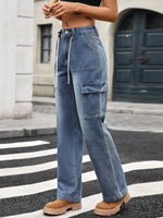 Person wearing blue jeans and brown shoes on a city street.
