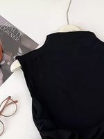 Black sleeveless top on a hanger with a magazine and glasses in the background
