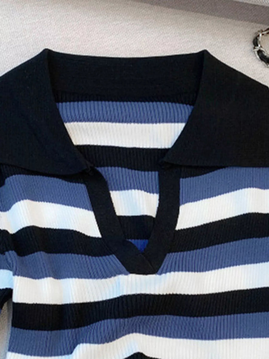 A close-up of a ribbed knit polo shirt with horizontal stripes in navy blue, medium blue, white, and black, featuring a solid black collar.