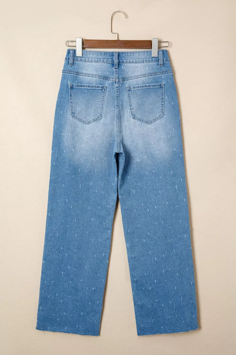 Light blue jeans on a hanger against a beige background