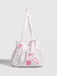 White drawstring bag with pink floral and musical note designs on a light gray background