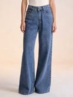 Person wearing blue flared jeans on a light background
