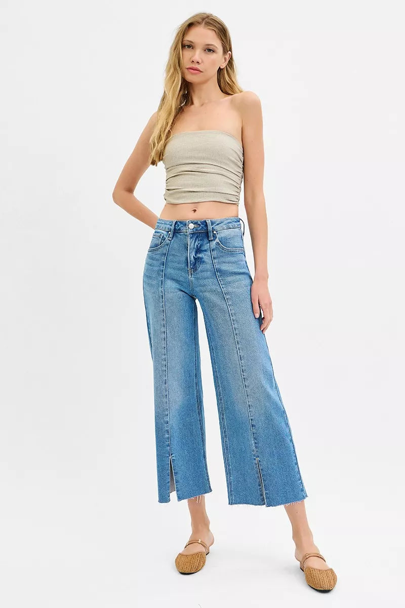 Woman wearing a beige strapless top and blue jeans on a white background