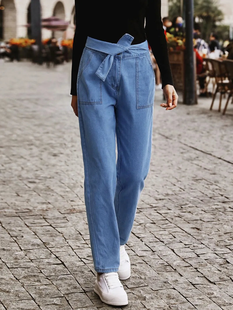 Person wearing blue pants and white sneakers on a cobblestone street.