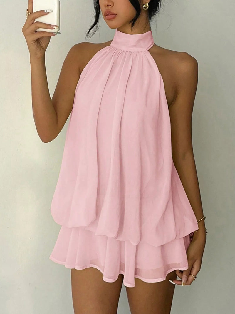 Woman wearing a pink halter neck dress against a plain background