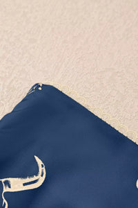 Navy blue fabric with a white bull logo on a beige textured background