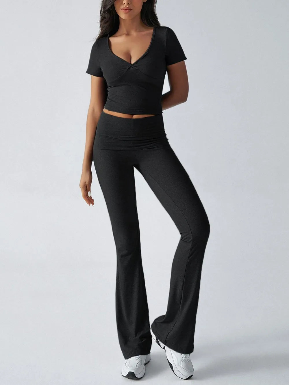 Woman wearing a black outfit with a top and pants on a white background