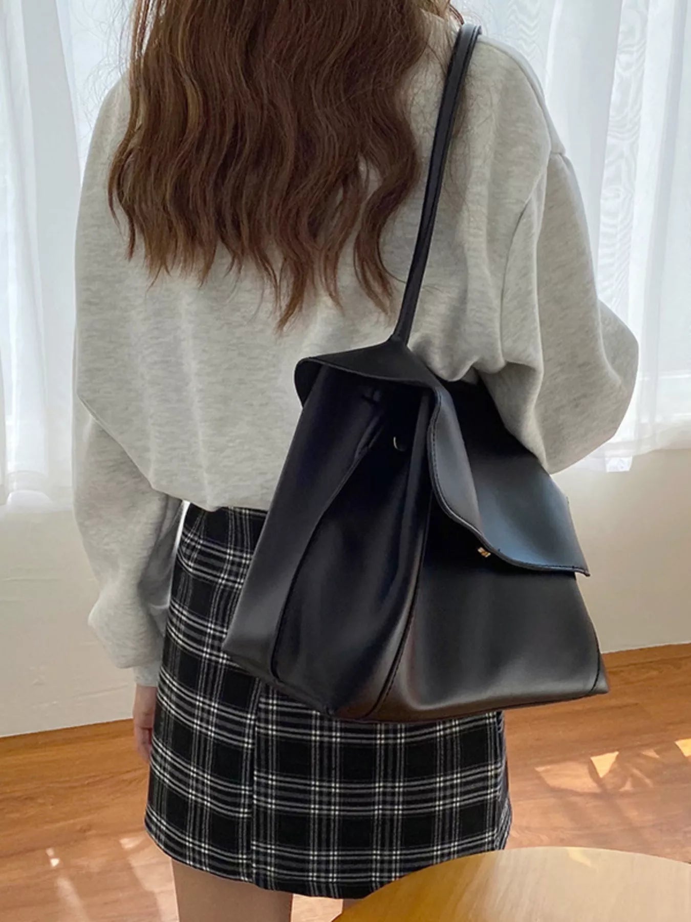 Person wearing a black leather bag over one shoulder indoors.