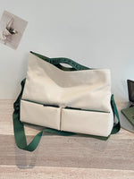 Beige tote bag with green straps on a wooden surface