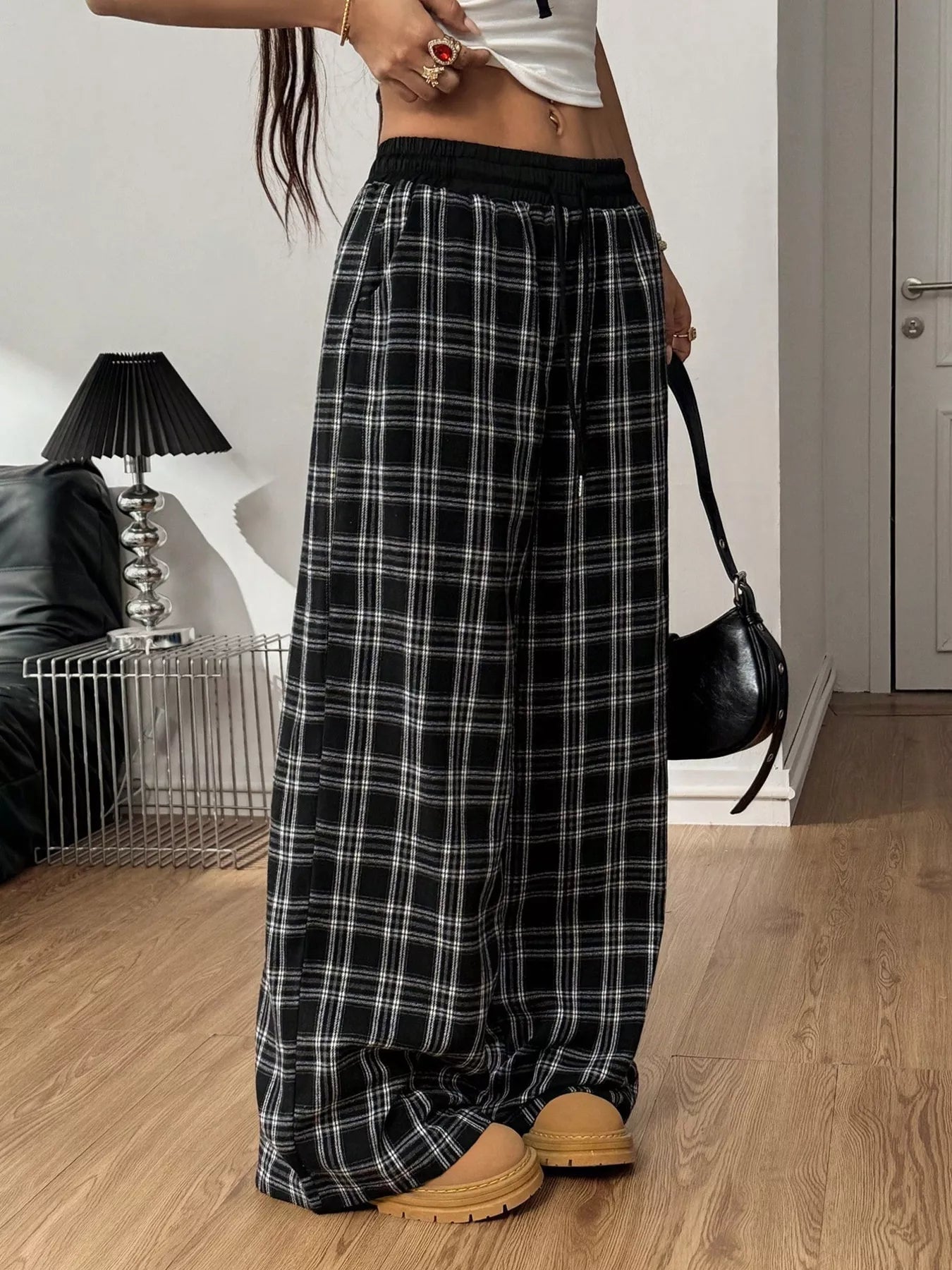 Person wearing black and white plaid pants in a room with a lamp and couch.