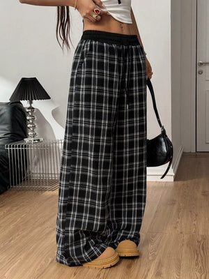 Person wearing black and white plaid pants in a room with a lamp and couch.