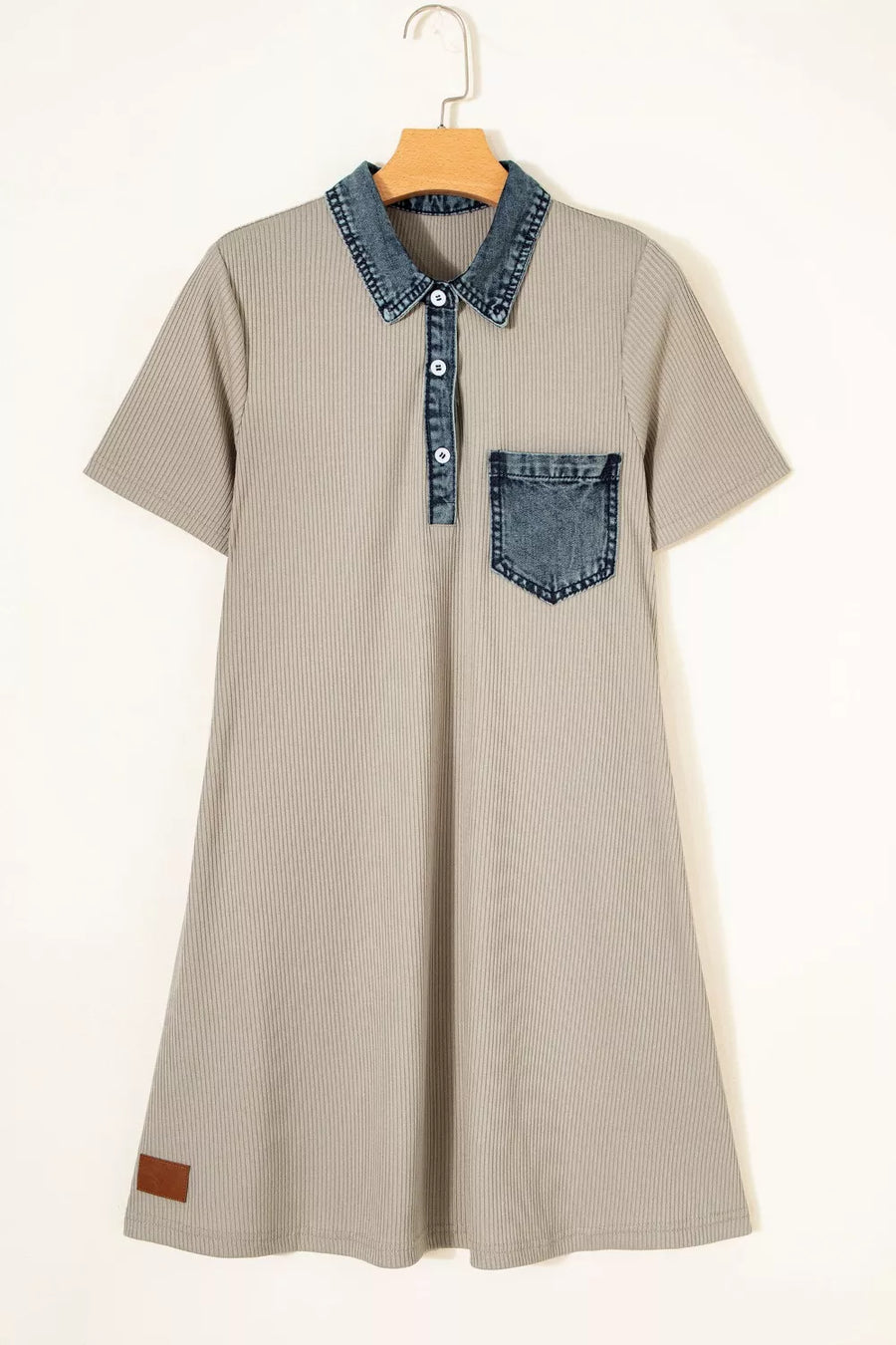 Beige dress with denim collar and pocket on a hanger against a white background