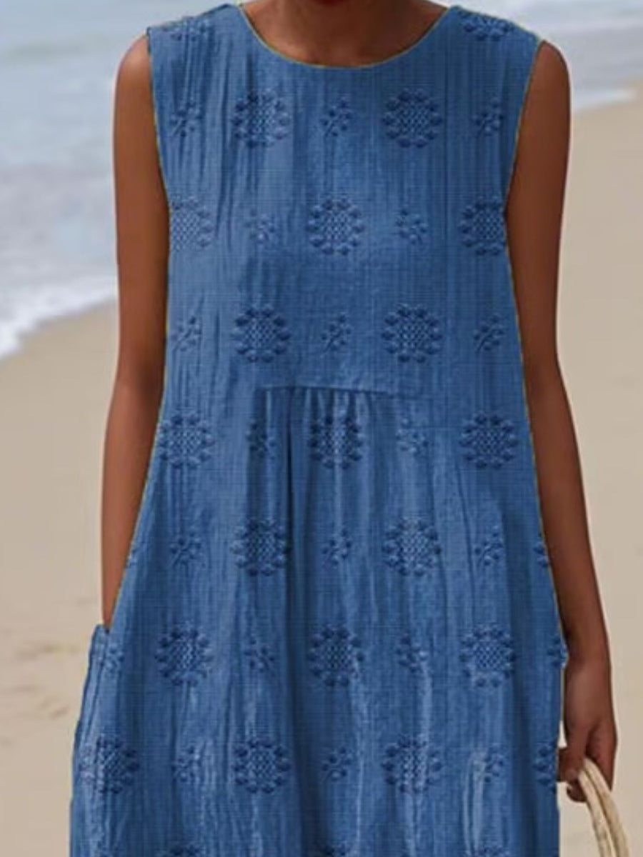 Woman wearing a blue dress with a geometric pattern on a beach.