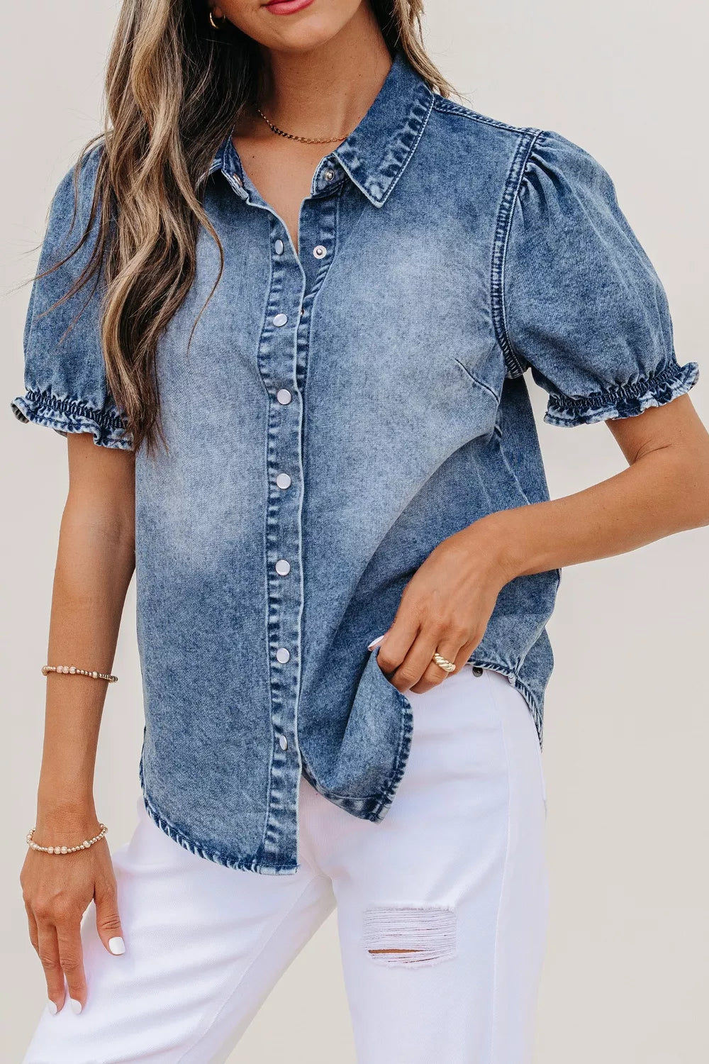 Woman wearing a denim shirt with puff sleeves against a neutral background