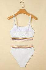 White bikini set with orange accents on a beige background