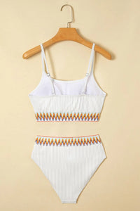 White bikini set with orange accents on a beige background