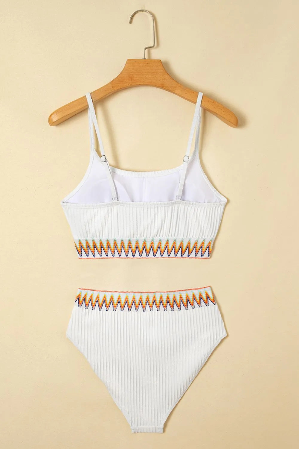 White bikini set with orange accents on a beige background