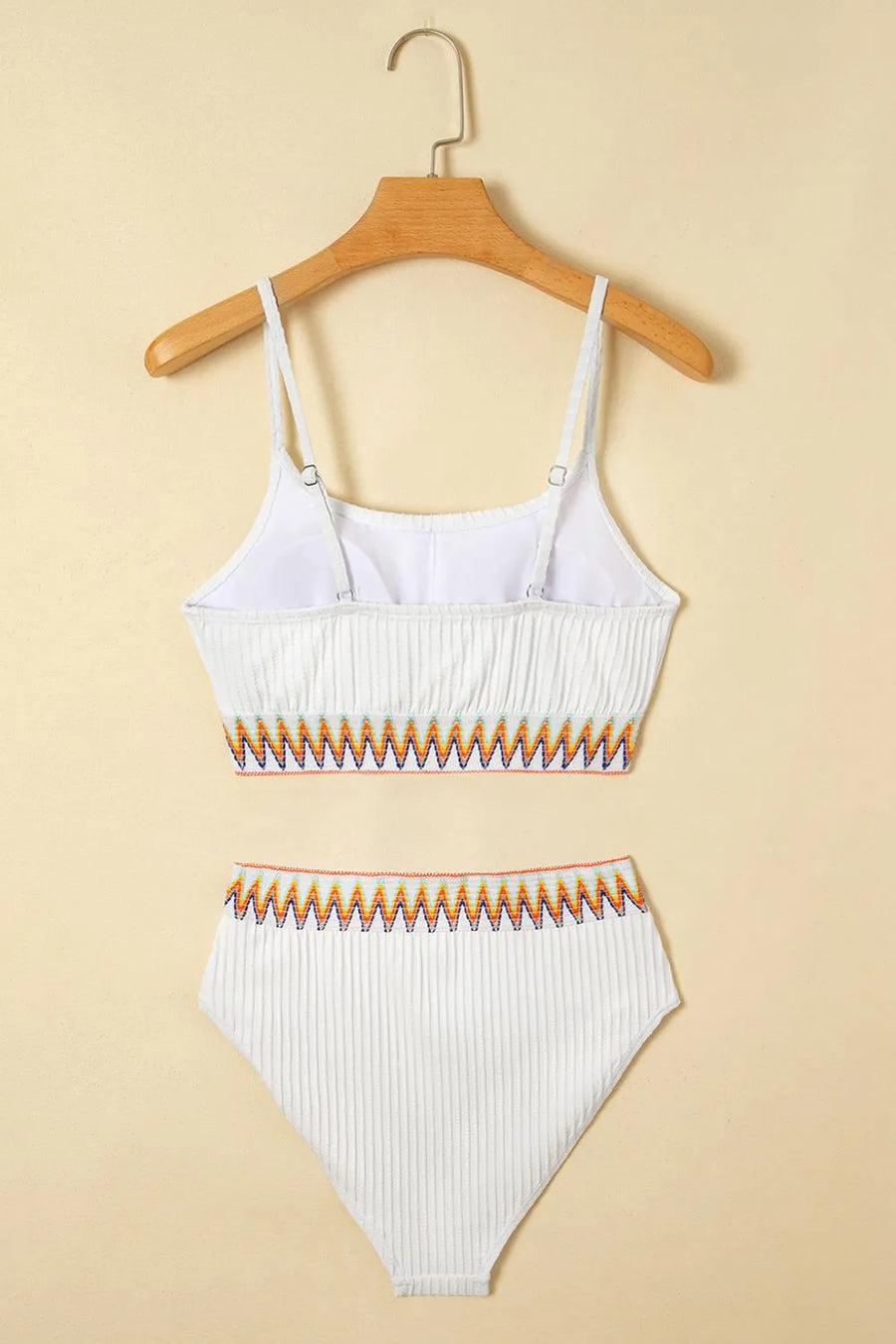 White bikini set with orange accents on a beige background
