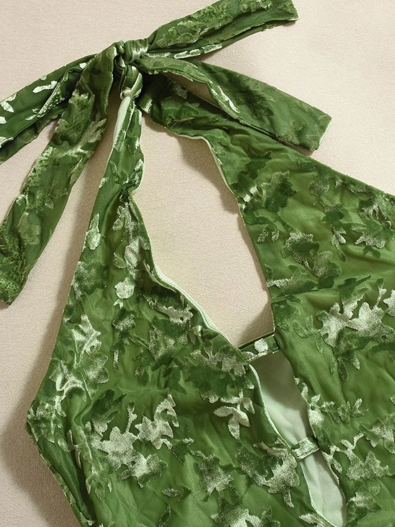 Green floral patterned top with a bow detail on a beige background