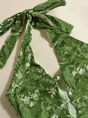 Green floral patterned top with a bow detail on a beige background