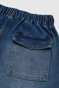 Close-up of blue denim shorts with a pocket on a light gray background