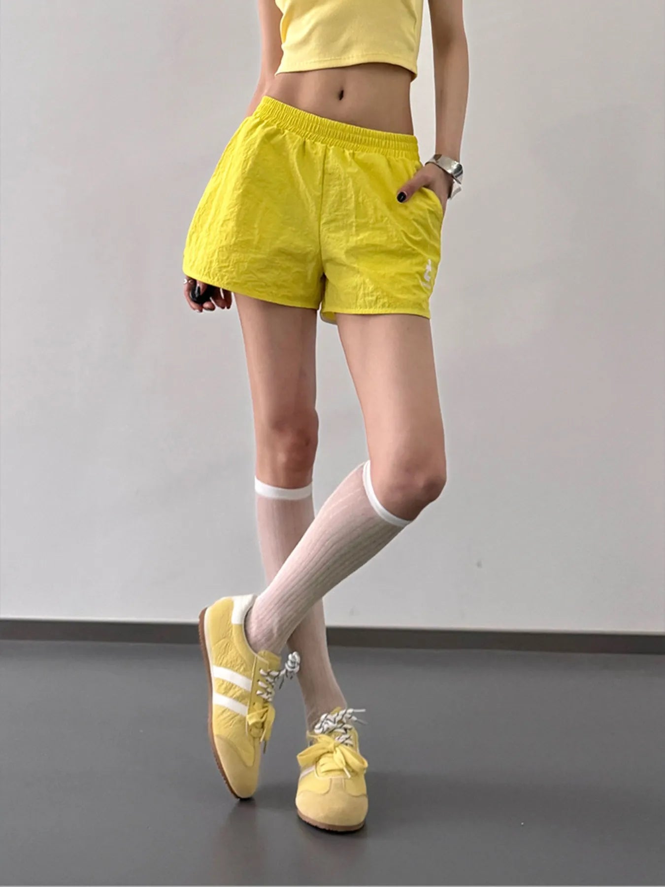 Person wearing yellow shorts and shoes on a plain background