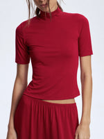 Red turtleneck top worn by a person on a white background