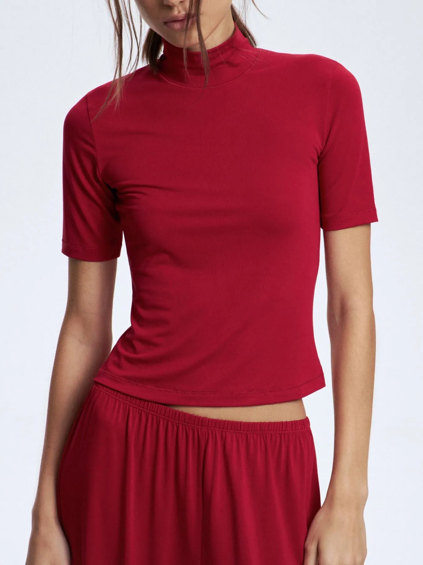 Red turtleneck top worn by a person on a white background