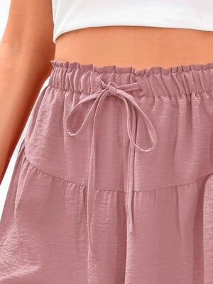Close-up of a person wearing a white top and pink tiered skirt.
