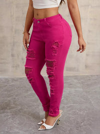 Person wearing bright pink distressed jeans on a neutral background