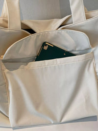 Beige tote bag with a green phone inside on a light gray background