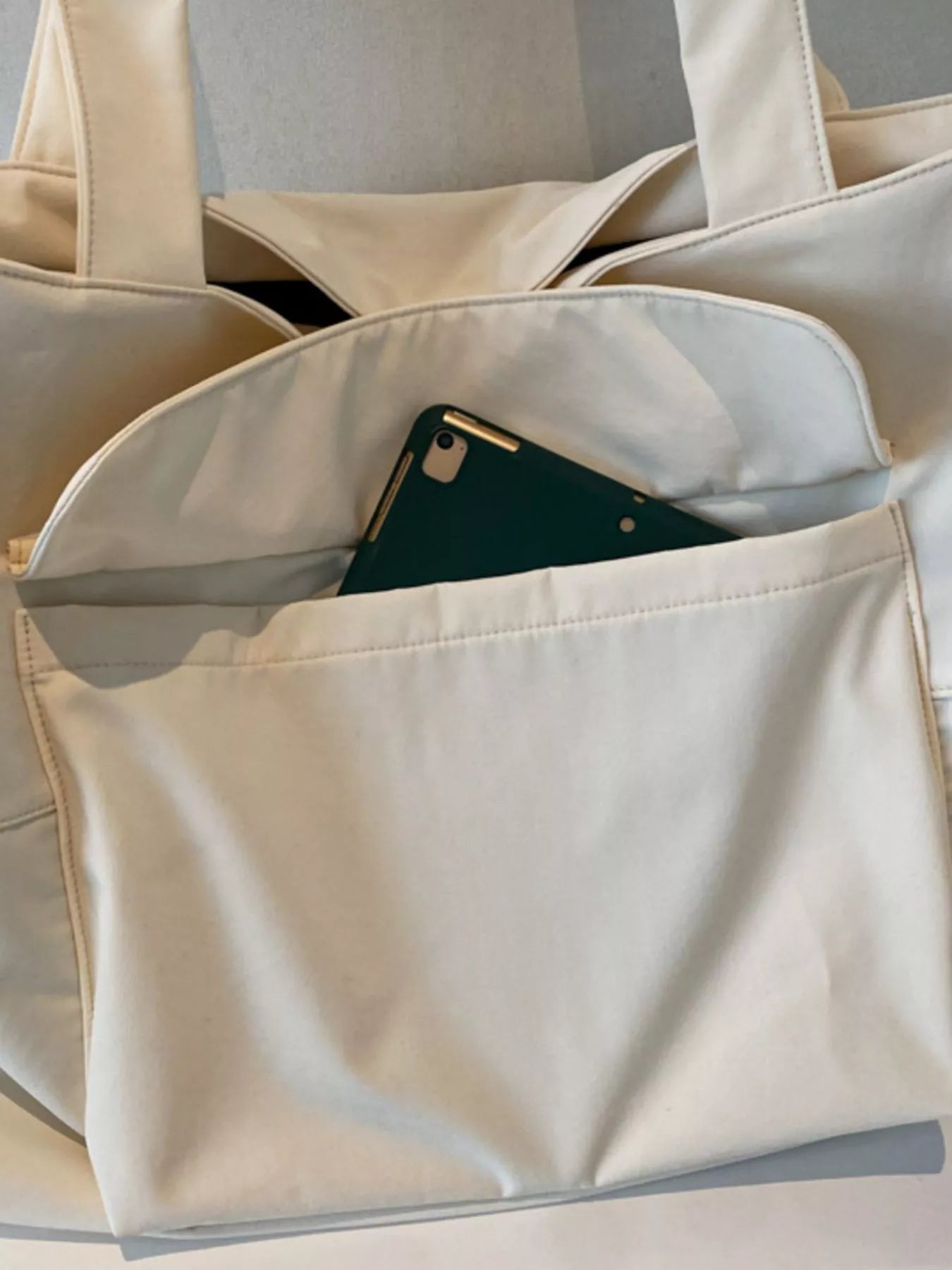 Beige tote bag with a green phone inside on a light gray background