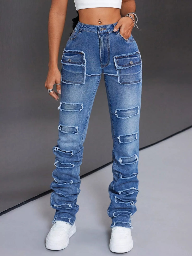 Person wearing high-waisted, distressed blue jeans on a gray background