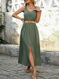Woman wearing a green dress with a belt, standing on a stone path.